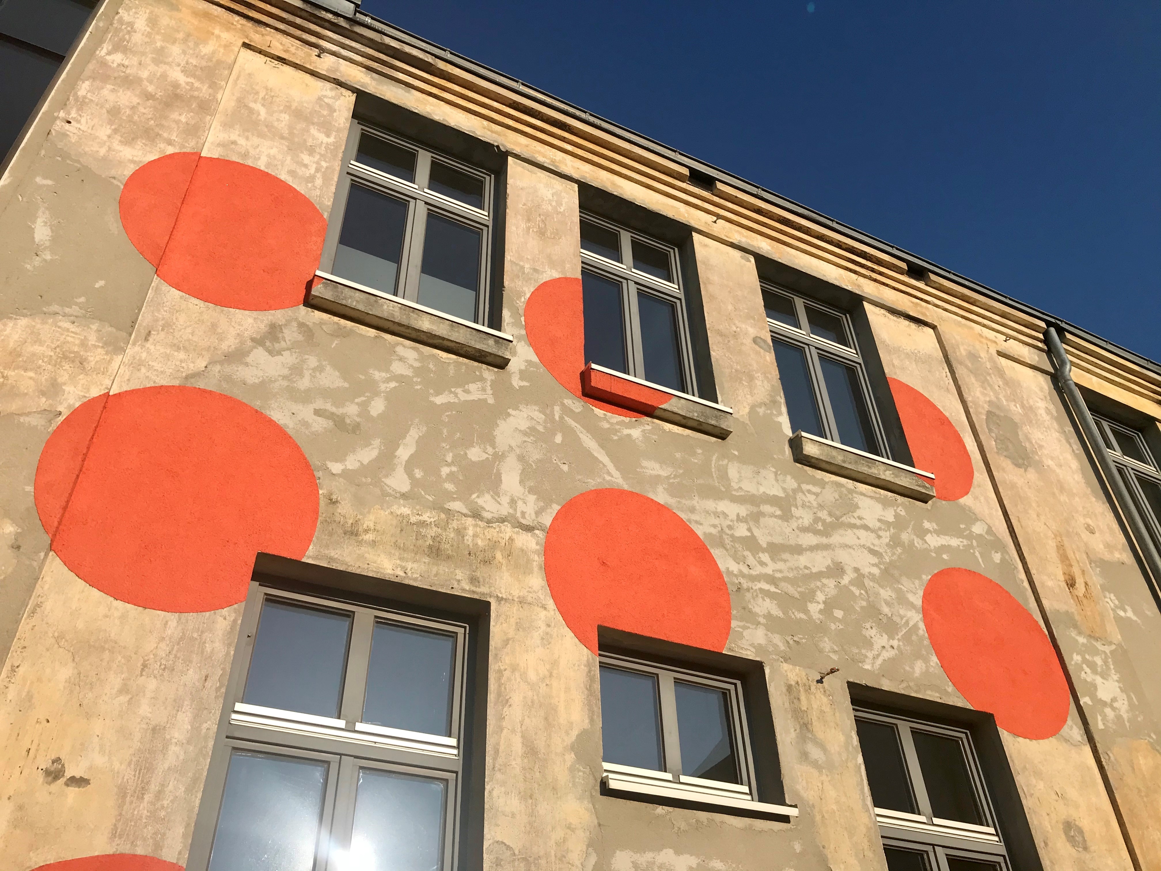 Fassade des Neuwerk-Gebäudes mit großen orangen Punkten vor blauem Himmel